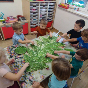 Dzieci malują farbami choinkę zrobioną z pianki uszczelniającej.