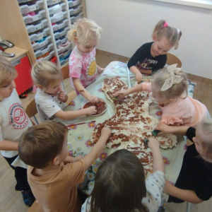 Dzieci malują farbami piernika zrobionego z pianki uszczelniającej.