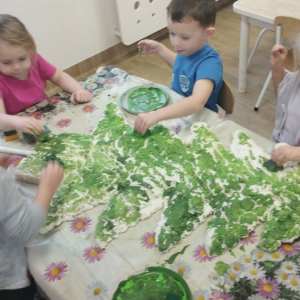 Dzieci malują farbami choinkę wykonaną z pianki uszczelniającej.