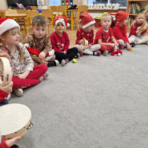 Dzieci grają na tamburynie, słuchając opowiadania muzycznego "Przyjazd Mikołaja"