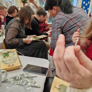 Rodzice podziwiają choinki na drewnie, które wykonały dzieci na zajęciach           