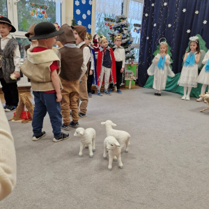 Pasterze stoją przy ognisku i rozmawiają o darach, które chcą podarować Dzieciątku Jezus