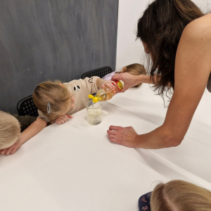 Dziewczynka wlewa olej do zlewki z wodą