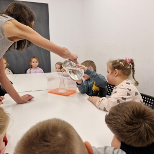 Chłopiec wlewa wodę do kolby stożkowej