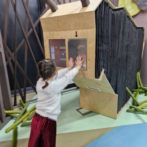 Dziewczynka próbuje swoich sił, naciskając na tablicę w konstrukcji przedstawiającej tura