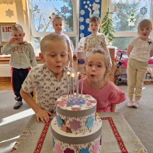 Bliźnięta zdmuchują świeczki na urodzinowym torcie