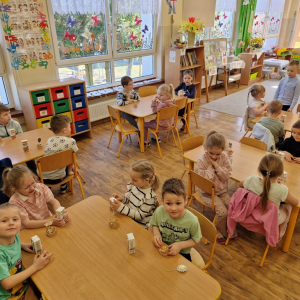 Chłopiec zaprasza do poczęstunku, życząc kolegom i koleżankom "smacznego"