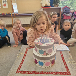 Solenizantka zdmuchuje świeczki na urodzinowym torcie   