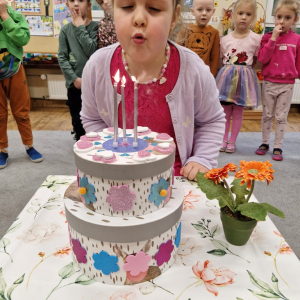 Dziewczynka zdmuchuje świeczki na urodzinowym torcie