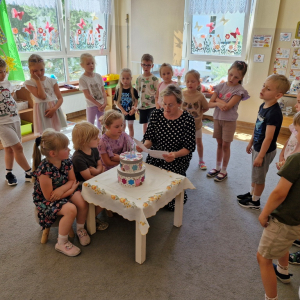 Wychowawczyni czyta tekst życzeń na urodzinowym torcie