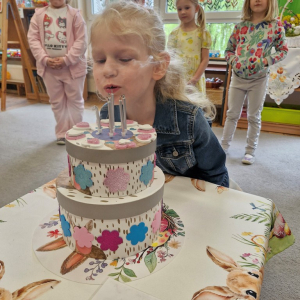 Dziewczynka zdmuchuje świeczki na urodzinowym torcie