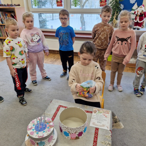 Dziewczynka ogląda upominki wyjęte z papierowego tortu