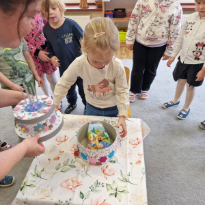 Dziewczynka otwiera tort, by zobaczyć upominek - niespodziankę urodzinową