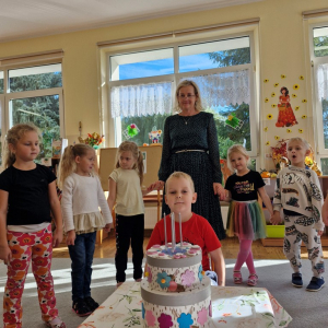 Chłopiec z dziećmi i Panią Marysią tuż po zdmuchnięciu świeczek na torcie urodzinowym