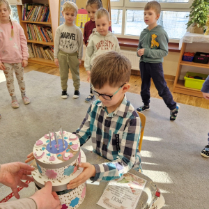 Chłopiec otwiera papierowy tort, aby wyjąć urodzinowy prezent