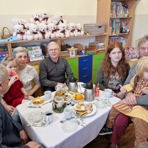 Babcia z wnuczką, dziadkowie i rodzice z synem w czasie poczęstunku