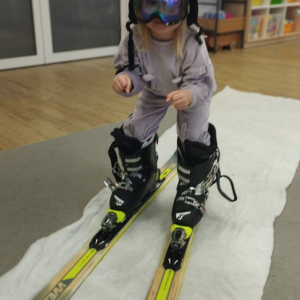 Dziecko przymierza strój i sprzęt narciarski.