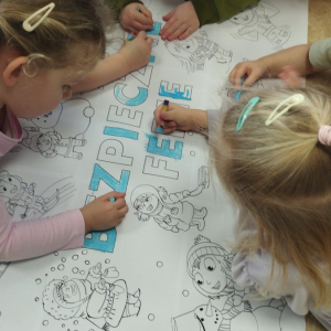 Dzieci kolorują plakat Bezpieczne ferie zimowe.