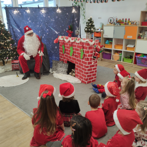 Dzieci siedzące w gromadce podczas wizyty Mikołaja