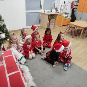 Dzieci siedzące w gromadce podczas wizyty Mikołaja