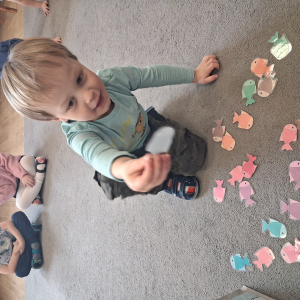 Dziecko wrzuca papierowe rybki ,karmi misia polarnego