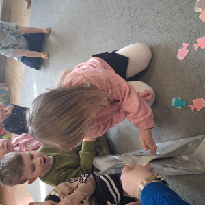 Dziecko wrzuca papierowe rybki ,karmi misia polarnego