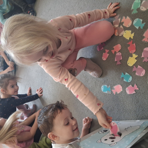 Dziecko wrzuca papierowe rybki ,karmi misia polarnego