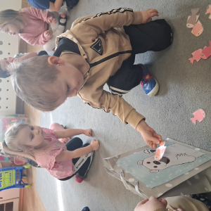 Dziecko wrzuca papierowe rybki ,karmi misia polarnego