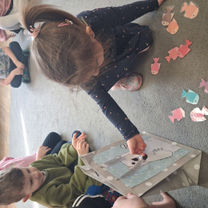 Dziecko wrzuca papierowe rybki ,karmi misia polarnego