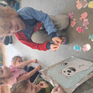 Dziecko wrzuca papierowe rybki ,karmi misia polarnego