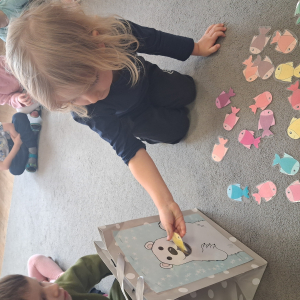 Dziecko wrzuca papierowe rybki ,karmi misia polarnego