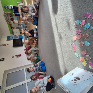 Dziecko wrzuca papierowe rybki ,karmi misia polarnego