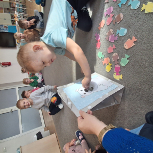 Dziecko wrzuca papierowe rybki ,karmi misia polarnego