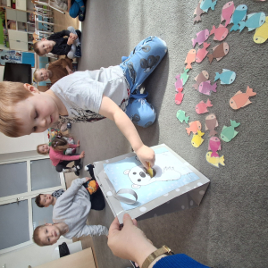 Dziecko wrzuca papierowe rybki ,karmi misia polarnego