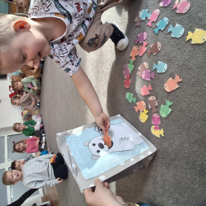 Dziecko wrzuca papierowe rybki ,karmi misia polarnego