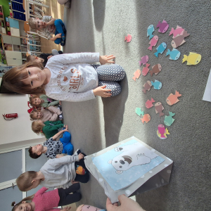 Dziecko wrzuca papierowe rybki ,karmi misia polarnego