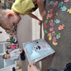 Dziecko wrzuca papierowe rybki ,karmi misia polarnego