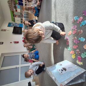 Dziecko wrzuca papierowe rybki ,karmi misia polarnego