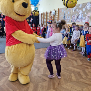 Dziewczynka tańczy z Kubusiem Puchatkiem