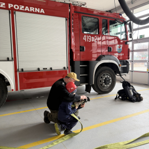 Zabawa edukacyjna z wężem strażackim - dzieci uczą się współpracy i koordynacji w zabawie z prawdziwym sprzętem. 