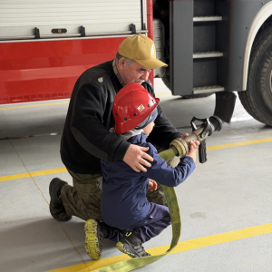 Zabawa edukacyjna z wężem strażackim - dzieci uczą się współpracy i koordynacji w zabawie z prawdziwym sprzętem. 