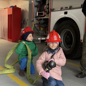 Zabawa edukacyjna z wężem strażackim - dzieci uczą się współpracy i koordynacji w zabawie z prawdziwym sprzętem. 