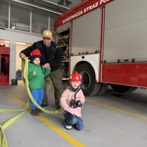 Zabawa edukacyjna z wężem strażackim - dzieci uczą się współpracy i koordynacji w zabawie z prawdziwym sprzętem. 