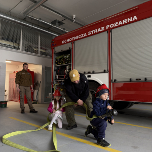 Zabawa edukacyjna z wężem strażackim - dzieci uczą się współpracy i koordynacji w zabawie z prawdziwym sprzętem. 