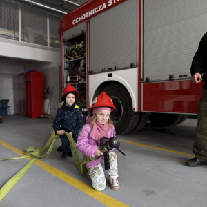 Zabawa edukacyjna z wężem strażackim - dzieci uczą się współpracy i koordynacji w zabawie z prawdziwym sprzętem. 