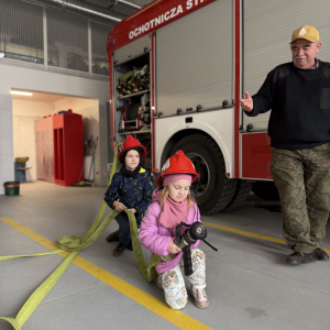 Zabawa edukacyjna z wężem strażackim - dzieci uczą się współpracy i koordynacji w zabawie z prawdziwym sprzętem. 
