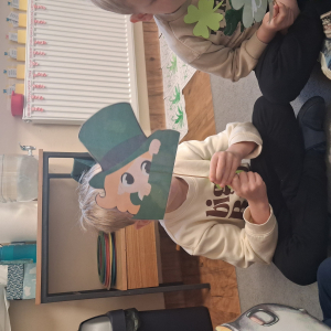 dziecko trzyma akcesoria do zdjeć z okazji Dnia Sw Patryka