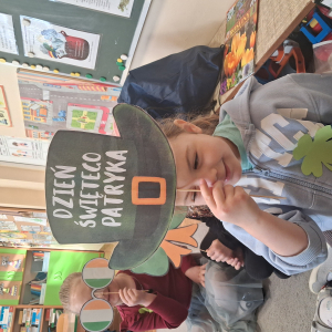 dziecko trzyma akcesoria do zdjeć z okazji Dnia Sw Patryka