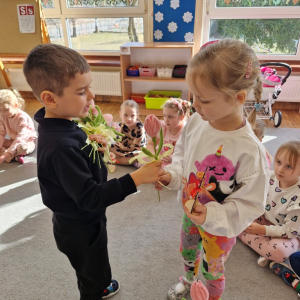 Chłopiec składa życzenia koleżance z grupy i wręcza tulipana z okazji Dnia Kobiet