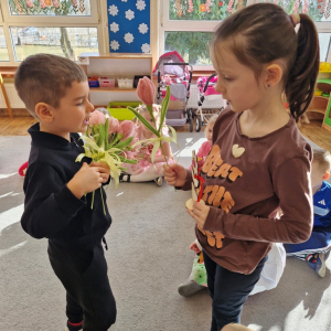 Chłopiec składa życzenia koleżance z grupy i wręcza tulipana z okazji Dnia Kobiet